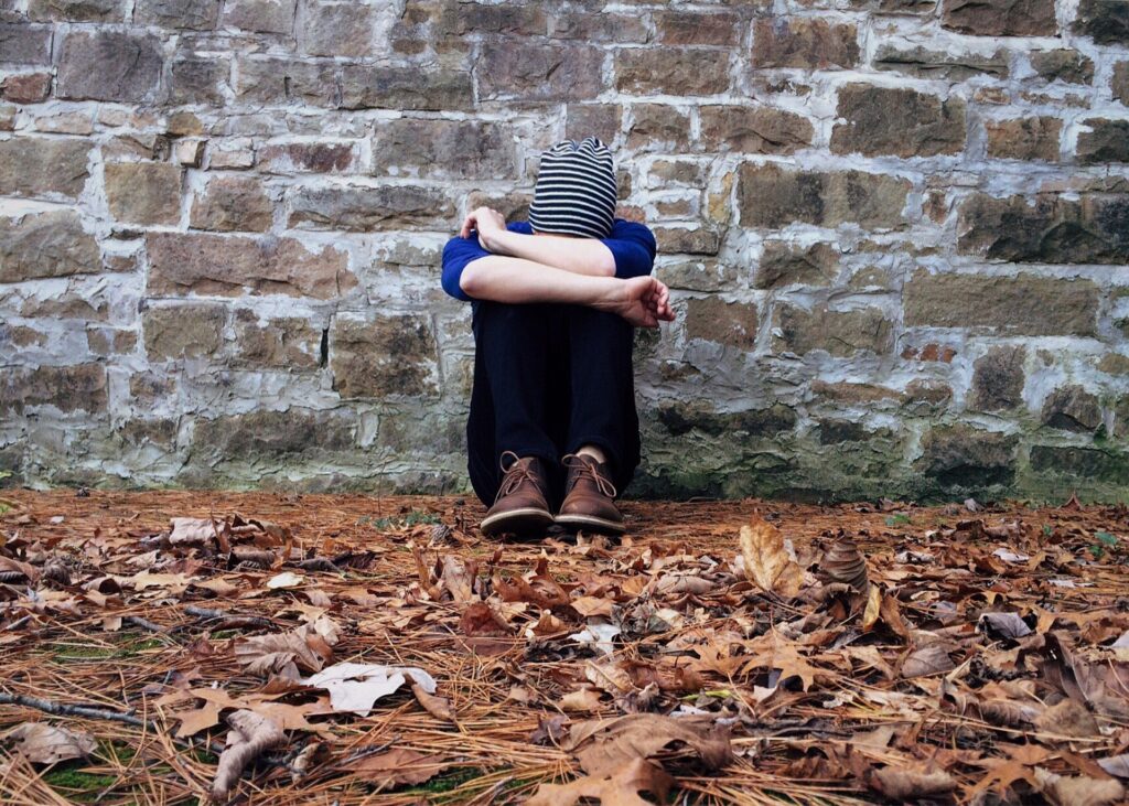 Causes of depression person crouched down feeling low 